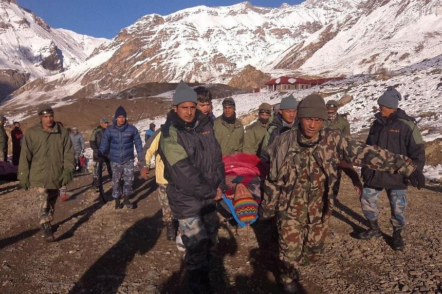 In this handout photograph released by the Nepal Army on Oct 15, 2014, an injured survivor of a snow storm is assisted by Nepal Army personel in Manang District, along the Annapurna Circuit Trek.&nbsp;Nepalese rescuers on Thursday scoured Himalayan h
