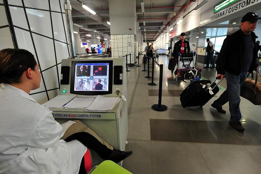 A health worker scans passengers with a thermal imaging camera upon their arrival at the Alexander the Great airport near Macedonia's capital Skopje on Oct 10, 2014. -- PHOTO: AFP