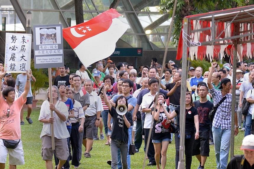 Han Hui Hui (with loudspeaker) and Roy Ngerng (carrying state flag) with supporters at the Return Our CPF rally, marching round the park at the conclusion of the rally on Sept 27, 2014.&nbsp;-- PHOTO: ST FILE