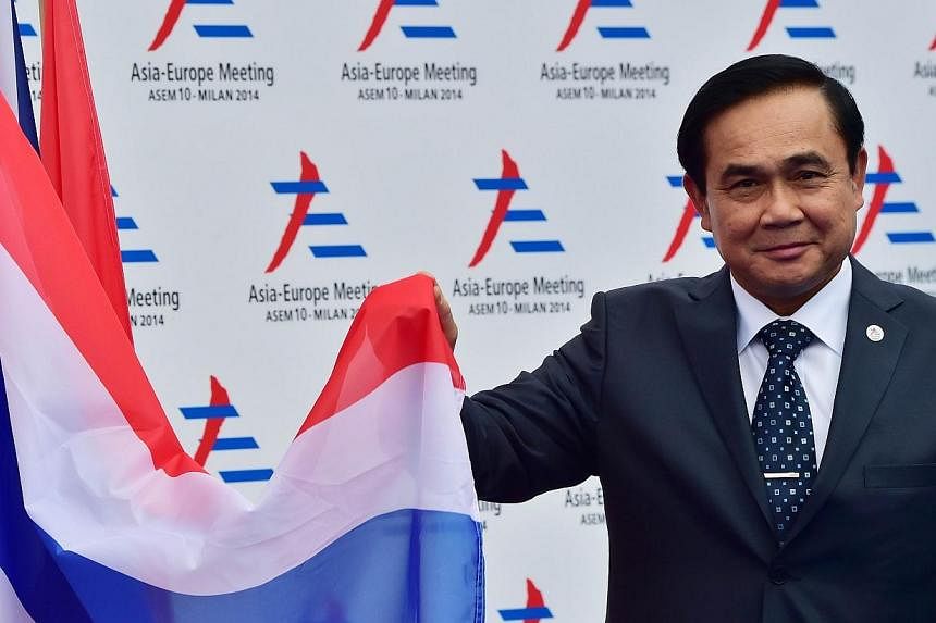 Thai junta leader and Prime Minister Prayuth Chan Ocha poses next to the Thai flag as he arrives to attend the 10th Asia-Europe Meeting (ASEM) on Oct 16, 2014, in Milan.&nbsp;Mr Prayuth slipped quietly into the club of world leaders Thursday against 