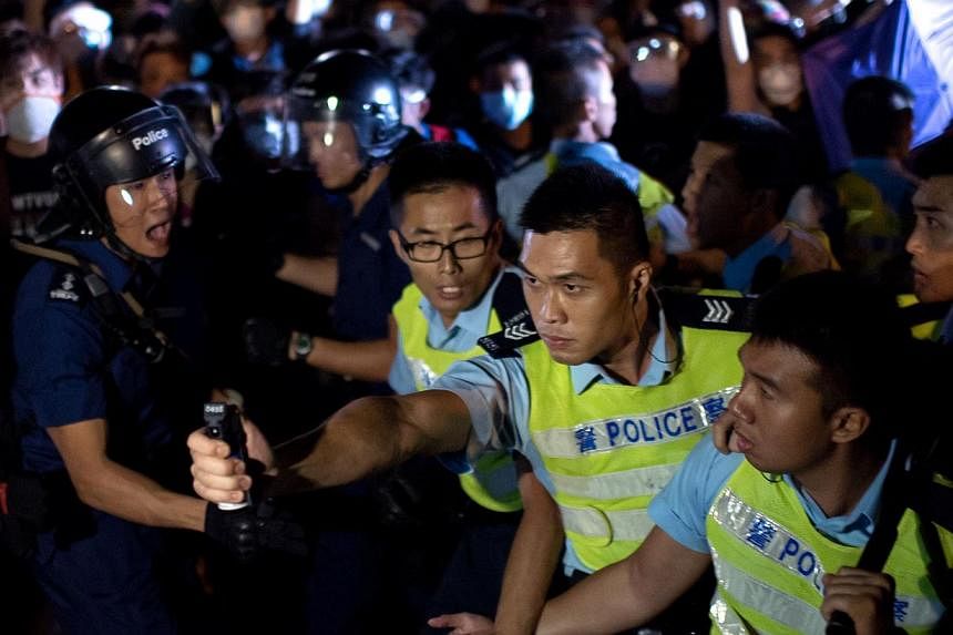 A police officer threatens to use pepper spray on a crowd of pro-democracy protesters in Hong Kong, on Oct 16, 2014. -- PHOTO: AFP