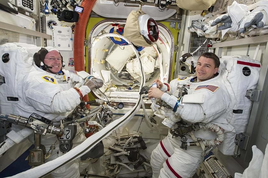 Nasa astronauts Reid Wiseman (right) and Barry Wilmore work inside the International Space Station on Oct 1, 2014. The two spacewalking Nasa astronauts hustled and muscled through an electrical repair job outside the International Space Station on Oc