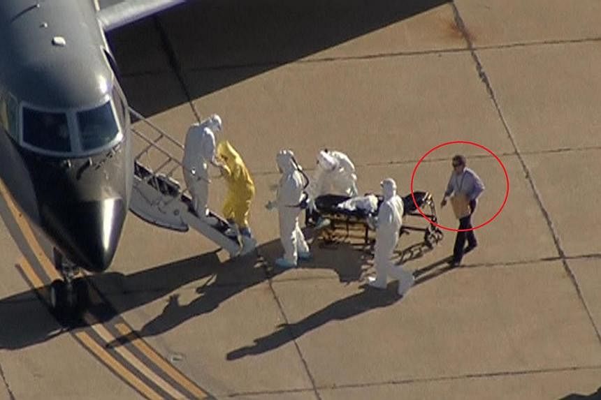 A screenshot shows "Clipboard Man" (circled) directing operations as nurse&nbsp;Amber Vinson, the second health-care worker to have become infected after treating Liberian patient&nbsp;Thomas Eric Duncan, is moved from Dallas to Atlanta. -- SCREENGRA