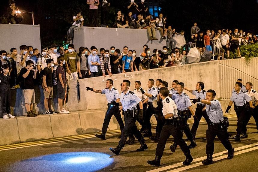 Police officers walk along a road on their way to forcing pro-democracy protesters to move back near the central government offices in Hong Kong on Oct 16, 2014. Hong Kong’s justice chief insisted Wednesday that any prosecution of plain-clothes off