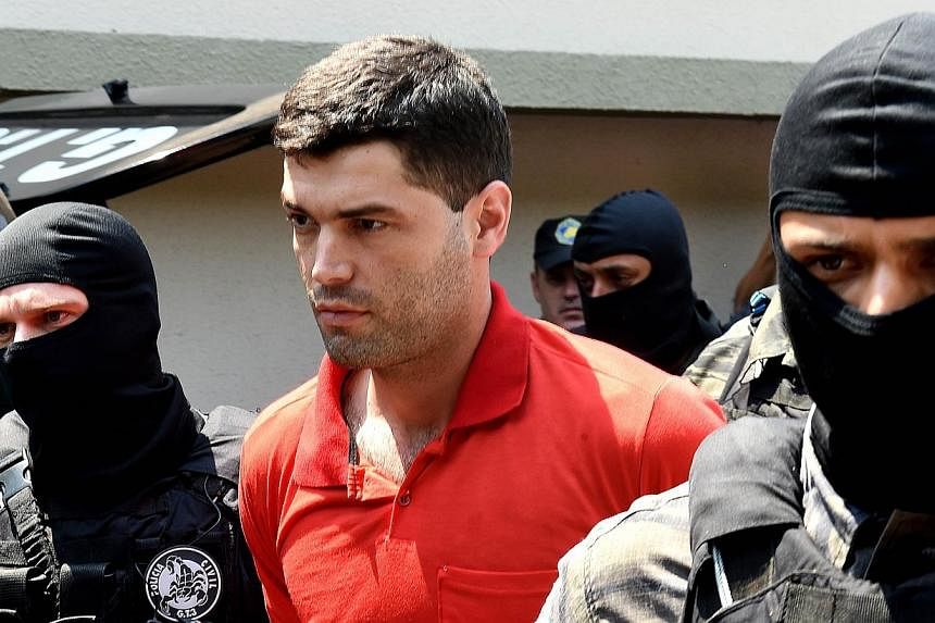 Alleged serial killer Thiago Henrique Gomes da Rocha&nbsp;(centre), suspected of killing 39 people, is escorted by police officers at the Department of Security, a day after his arrest, in Goiania, state of Goias, Brazil, on Oct 16, 2014. -- PHOTO: A