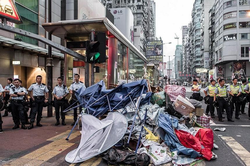 Police forces stand next to what is left of an encampment of pro-demoracy protesters in the Mong Kok district of Hong Kong, on Oct 17, 2014. -- PHOTO: AFP