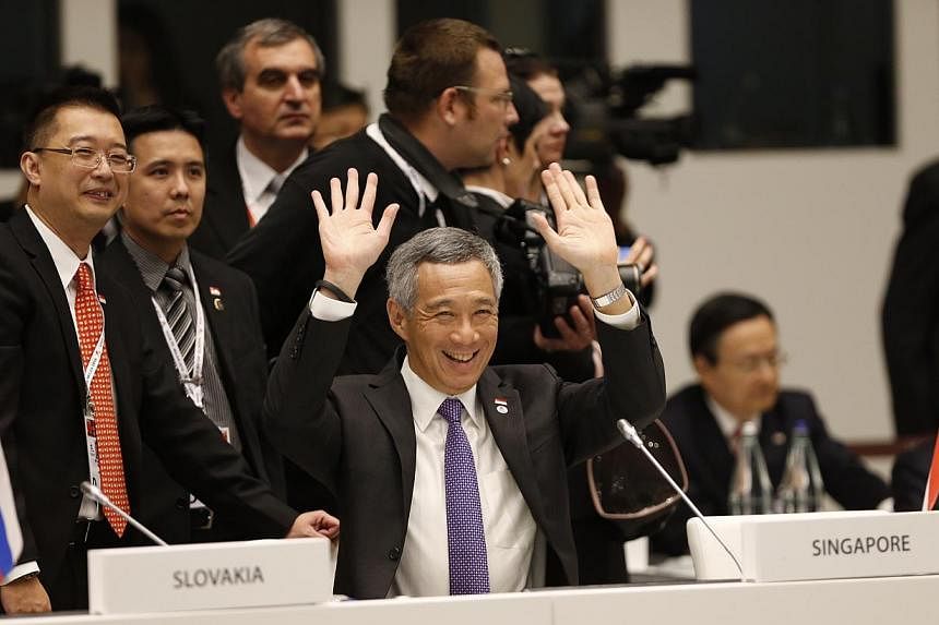 PM Lee Hsien Loong - seen with Ministry of Foreign Affairs deputy secretary Simon Wong (far left) - waving to fellow Asian and European leaders at the opening ceremony of the Asia-Europe Meeting in Milan yesterday.