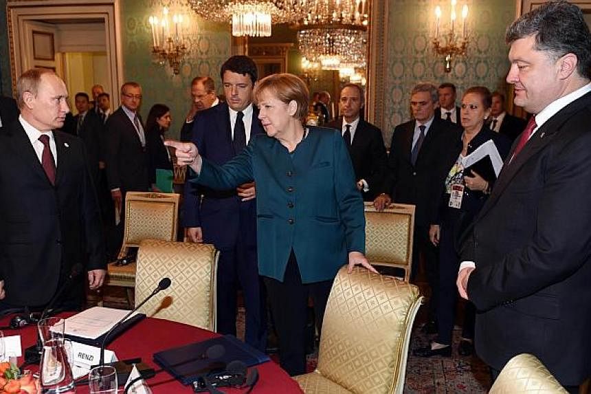 German Chancellor Angela Merkel (middle) gestures as she arrives for a meeting on Ukraine's crisis with Ukraine's President Petro Poroshenko (right), Russia's President Vladimir Putin (left) and Italian Prime Minister Matteo Renzi (2nd left) on Oct 1