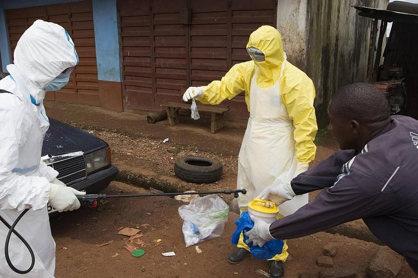 Health workers in protective equipment handle a sample taken from the body of someone who is suspected to have died from Ebola virus, near Rokupa Hospital, Freetown on Oct 6, 2014. -- PHOTO: REUTERS