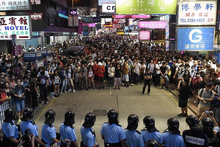 Pro-democracy demonstrators face police during a standoff amid ongoing protests in the Mongkok district of Hong Kong on Oct 17, 2014. Fresh clashes broke out as pro-democracy demonstrators attempted to take back a protest camp in a densely populated 