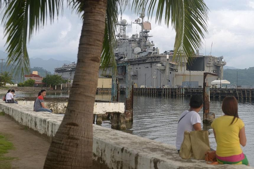 Students looking on alongside the USS Peleliu in the northern Philippine port city of Olongapo on Octobar 14, 2014. The two ships were in the Philippines for just-concluded joint amphibious opeation exercises. However the USS Peleliu may be staying l