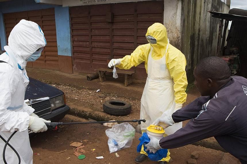 Health workers in protective equipment handle a sample taken from the body of someone who is suspected to have died from Ebola virus, near Rokupa Hospital, Freetown Oct 6, 2014.&nbsp;Ebola has killed at least two people in what was the last remaining