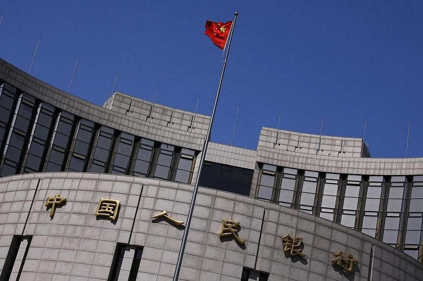 A Chinese national flag flutters outside the headquarters of the People's Bank of China, the Chinese central bank, in Beijing. -- PHOTO: REUTERS