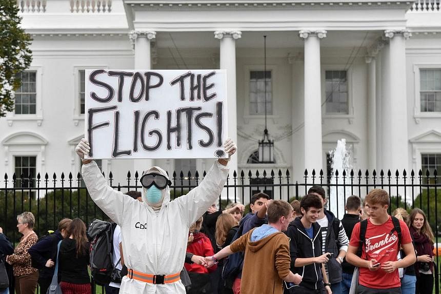 Jeff Hulbert from Annapolis, Maryland, dressed in a protective suit and mask, holds a poster demanding a halt to all flights from West Africa, as he protests outside the White House in Washington, DC on Oct 16, 2014. Top US health officials faced a g