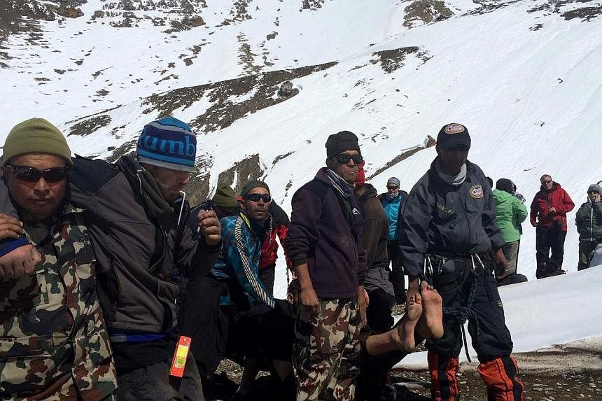A survivor injured in a snowstorm is carried on a stretcher by Nepal Army personnel to an army helicopter in the Manang district along the Annapurna Circuit Trek on Oct 17, 2014. -- PHOTO: AFP/NEPAL ARMY