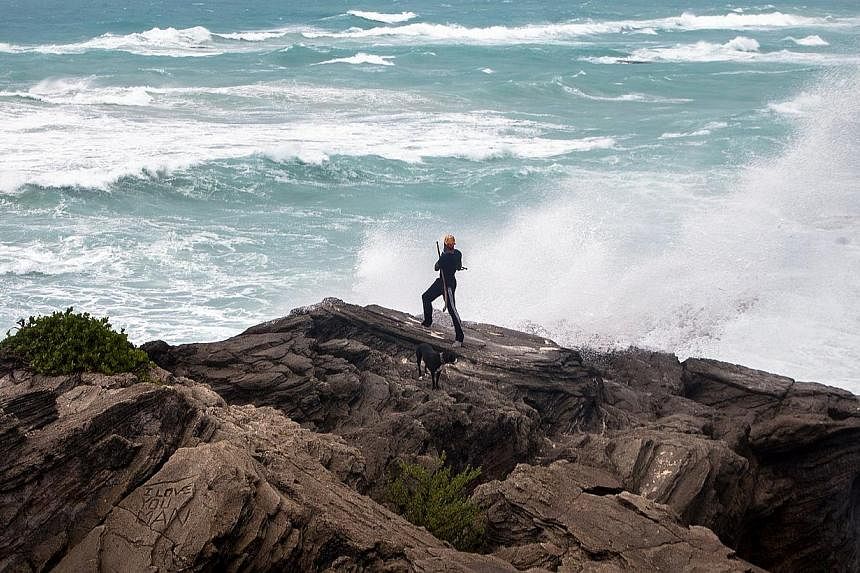 A man takes photos while standing on a cliff on the island's south shore as it is battered by winds from approaching Hurricane Gonzalo, in Astwood Park, Oct 17, 2014. -- PHOTO: REUTERS