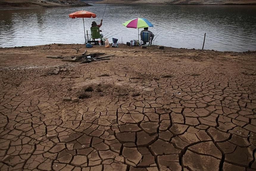 Men fish next to cracked ground as the Atibainha dam lake dries up due to a prolonged drought in Nazare Paulista, Sao Paulo state, on Oct 17, 2014. -- PHOTO: REUTERS
