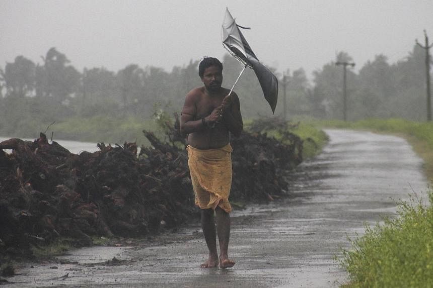 &nbsp;A man struggles with an umbrella in strong winds and rain caused by Cyclone Hudhud in Gopalpur in Ganjam district in the eastern Indian state of Odisha on Oct 12, 2014.&nbsp;The death toll from a cyclone that hit India's east coast last week ha