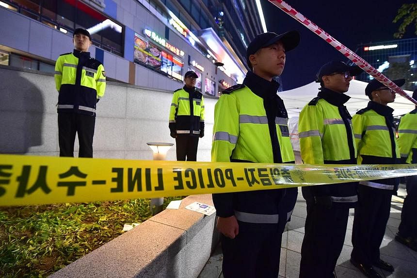 Policemen stand guard near a broken ventilation grate after concertgoers fell through it into an underground parking area below in Seongnam City, south of Seoul on Oct 17, 2014. -- PHOTO: AFP