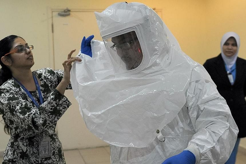 A medical worker is help to wearing protective gears against Ebola during a preparedness and response by the Malaysian Ministry of Health in an event of an outbreak of Ebola in Putrajaya on Oct 17, 2014. -- PHOTO: AFP