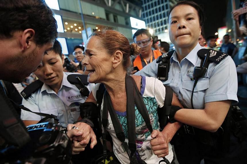 Police officers detaining Getty Images photographer Paula Bronstein during a confrontation between police and pro-democracy protesters at Mongkok shopping district in Hong Kong on October 17, 2014. Hong Kong riot police used pepper spray and baton ch