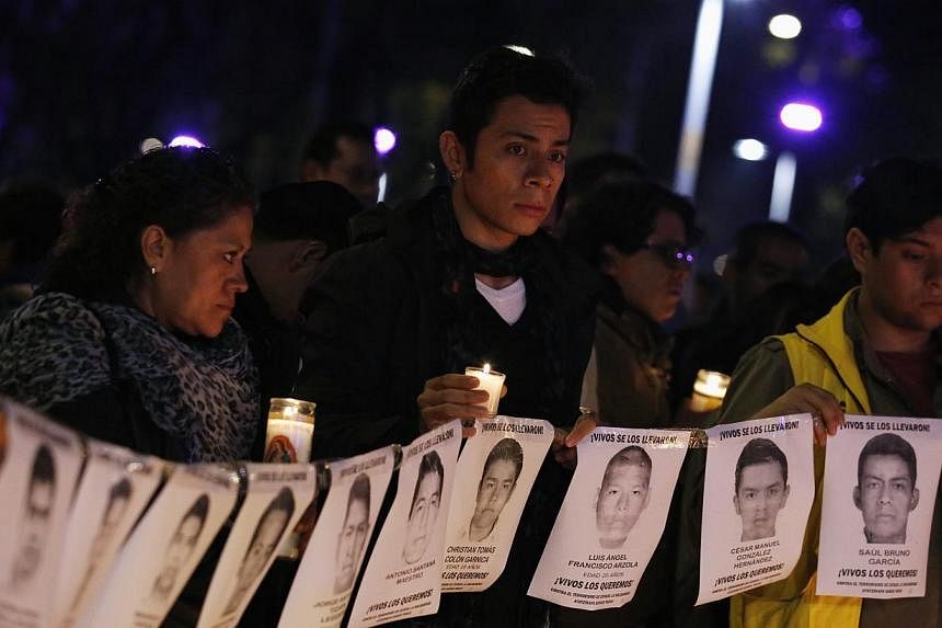 Protesters and members of Amnesty International hold photographs of missing students outside the building of the office of Mexico's Attorney-General, during a protest supporting the Ayotzinapa Teacher Training College missing students, in Mexico City