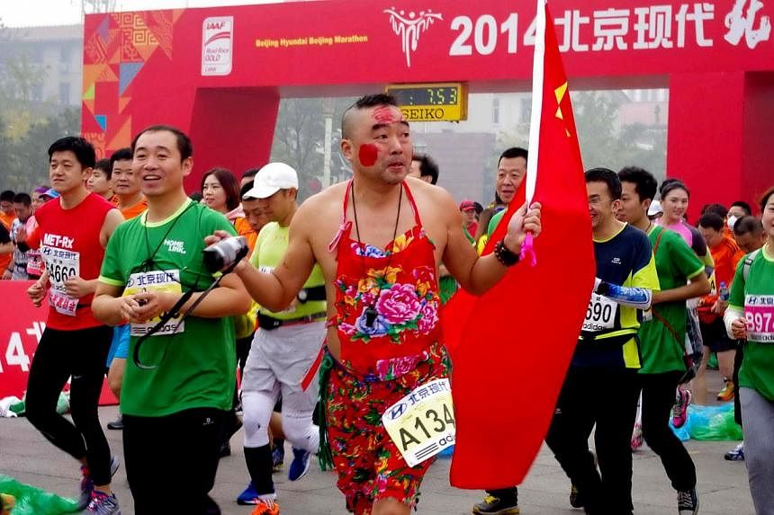 A runner in a fancy costume takes part in the 34th Beijing International Marathon which began at Tiananmen Square in Beijing on Oct 19, 2014, with many of the tens of thousands of participants wearing face masks, as the 42-kilometer course ended at t