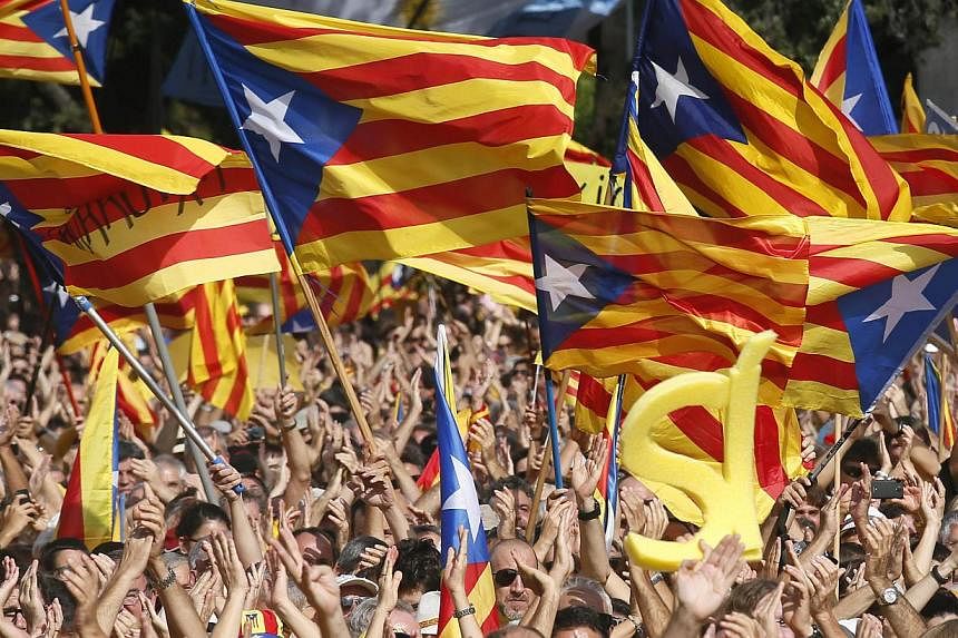 People wave their "Esteladas" (Catalonian separatist flag) flags during a Catalan pro-independence demonstration at Catalunya square in Barcelona on Oct 19, 2014.&nbsp;Tens of thousands of Catalans crowded central Barcelona on Sunday calling for earl