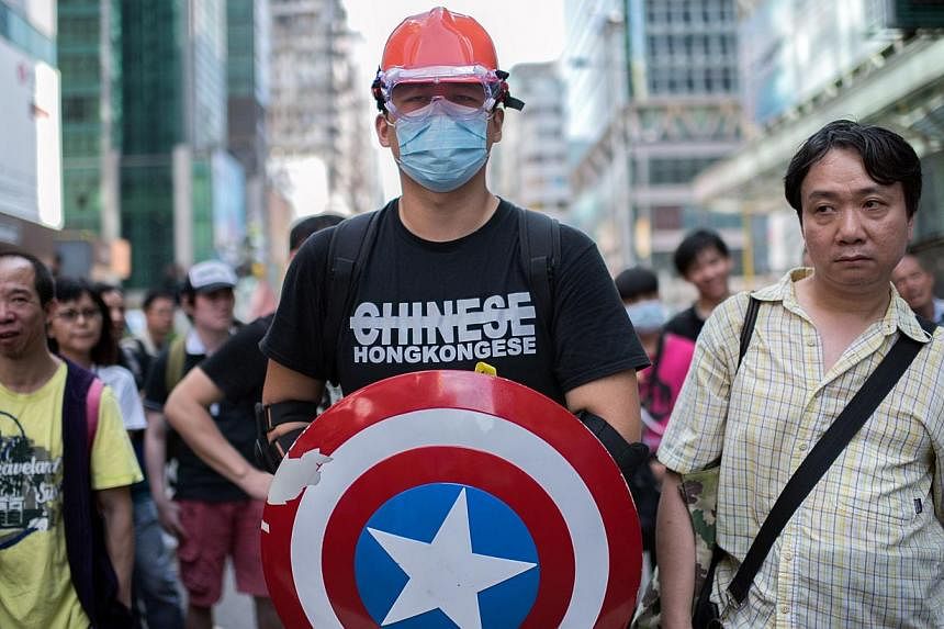 A man wearing protective gear and carrying a shield from the "Captain America" comic book series stands guard next to a pro-democracy protest barricade in the Mongkok district of Hong Kong on Oct 19, 2014.&nbsp;-- PHOTO: AFP