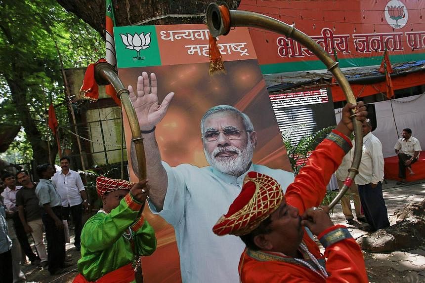Musicians play instruments in front of the portrait of Indian Prime Minister Narendra Modi, outside the Bharatiya Janata Party (BJP) party office in Mumbai on Oct 19, 2014.&nbsp;-- PHOTO: REUTERS