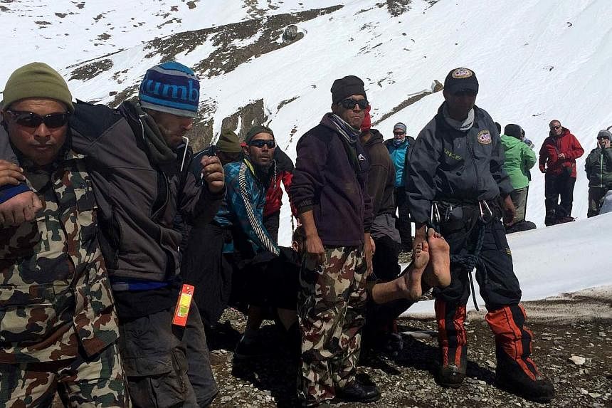 In this handout photograph released by the Nepal Army on Oct 17, 2014, a survivor injured in a snowstorm is carried on a stretcher by Nepal Army personnel to an army helicopter in the Manang district along the Annapurna Circuit Trek.&nbsp;Hopes faded