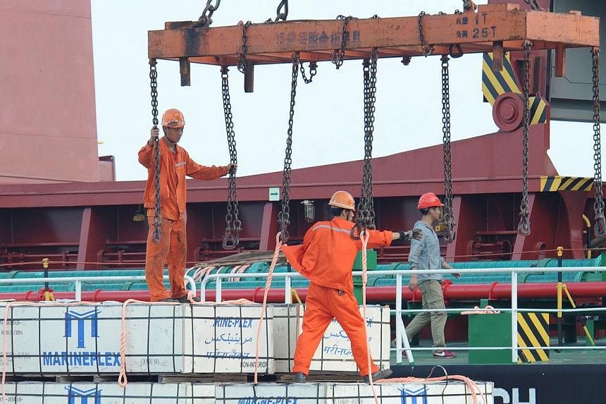 Workers load goods on a cargo ship at Lianyungang port in Lianyungang, east China's Jiangsu province on Aug 8, 2014. -- PHOTO: AFP