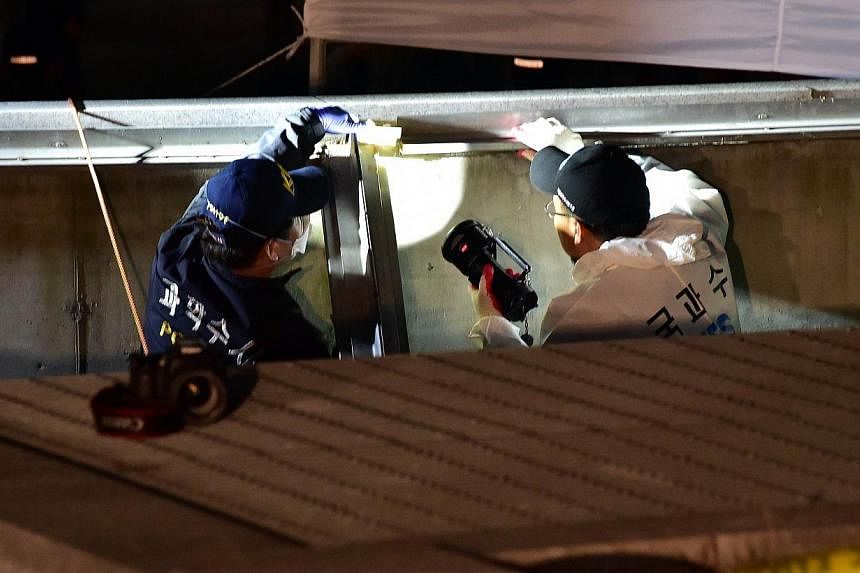 South Korean National Forensic Service members check a broken ventilation grate after concert goers fell through it into an underground parking area below in Seongnam City, south of Seoul, on Oct 17, 2014. -- PHOTO: AFP