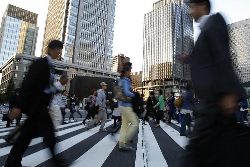 People cross a street at Tokyo's business district on Oct 17, 2014.&nbsp;The junior partner in Japanese Prime Minister Shinzo Abe's coalition government on Monday called for steps to stimulate an economy hit by April's sales tax rise and to soften th