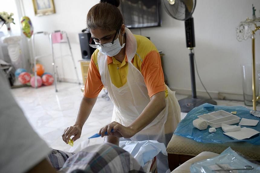 Senior Enrolled Nurse Sakina Bibi, 47, from NTUC Health, changing a wound dressing for an elderly patient in his flat. Home-care nurses must be able to cope effectively even with few resources at hand.