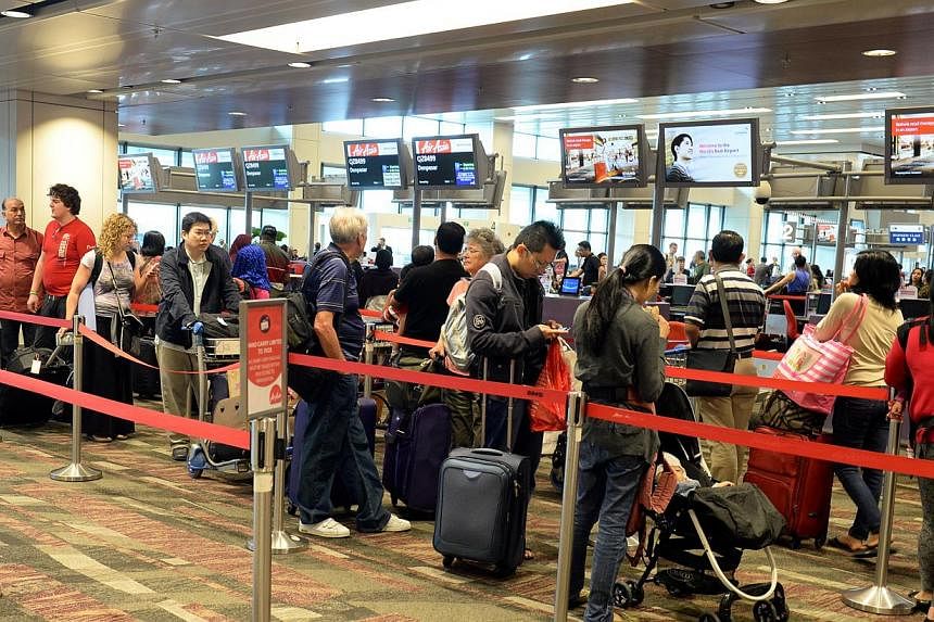 Passengers waiting to check in at the AirAsia counter at Changi Airport Terminal 1. -- PHOTO: ST FILE