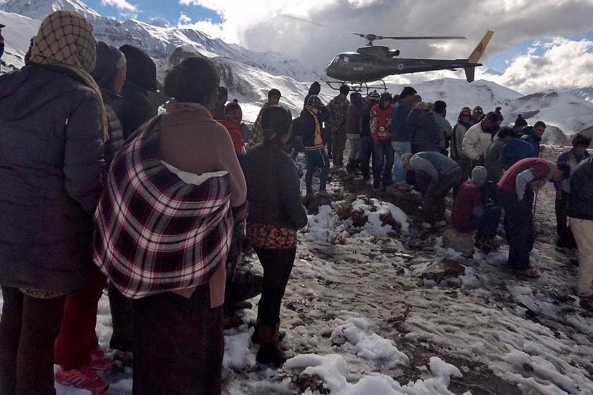 In this handout photograph released by the Nepal Army on Oct 15, 2014, a Nepalese Army helicopter rescues survivors of a snow storm in Manang District, along the Annapurna Circuit Trek. -- PHOTO: AFP