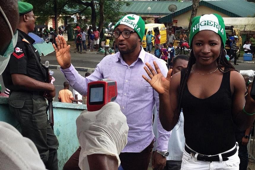 A picture taken on Sept 6, 2014 shows Nigeria supporters having their temperature taken with infrared thermometers prior to entering the UJ Esuene Stadium in Calabar to watch the 2015 African Cup of Nations qualifying football match between Nigeria a