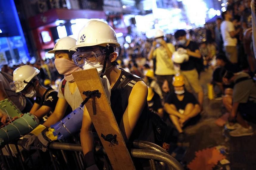 Pro-democracy protesters stand by a barricade as they prepare for a confrontation with riot police at the Mongkok shopping district of Hong Kong on Oct 19, 2014. -- PHOTO: REUTERS
