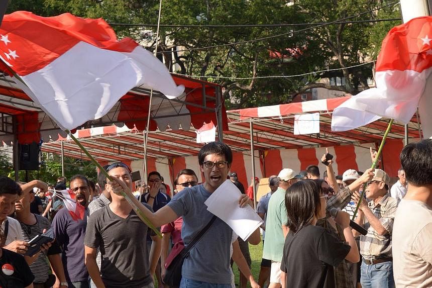 Roy Ngerng waving the Singapore flag as he led protesters at Hong Lim Park on Sept 27, 2014. They marched through a charity carnival by YMCA, scaring the children with special needs, and adults performing on stage. -- ST FILE PHOTO: LIM SIN THAI&nbsp