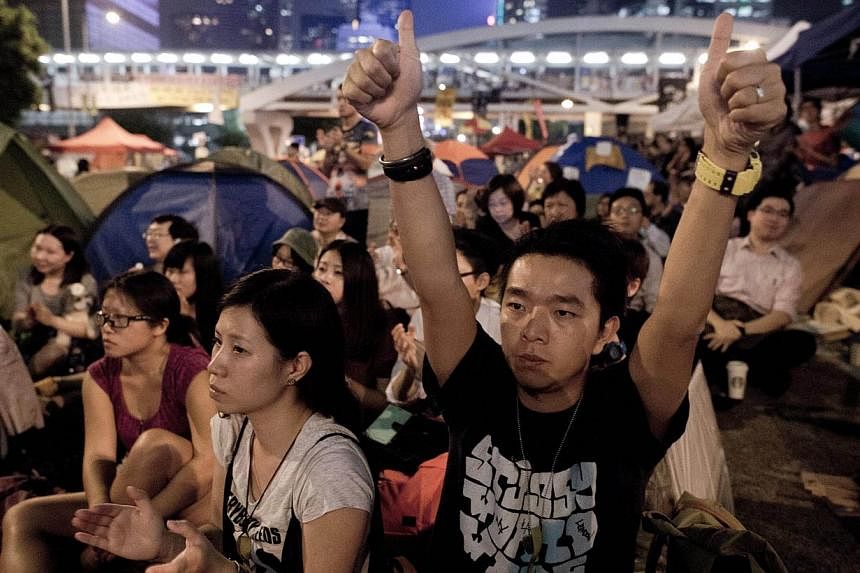 Pro-democracy demonstrators react as they watch a live transmission on a giant screen of talks with leaders of the Hong Kong Federation of Students and Hong Kong authorities, in the Admiralty district of Hong Kong on Oct 21, 2014.&nbsp;-- PHOTO: AFP