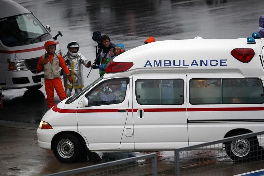 Marshalls clear the way for an ambulance after the race was stopped following a crash by Marussia Formula One driver Jules Bianchi of France at the Japanese F1 Grand Prix at the Suzuka Circuit on Oct 5, 2014. -- PHOTO: REUTERS