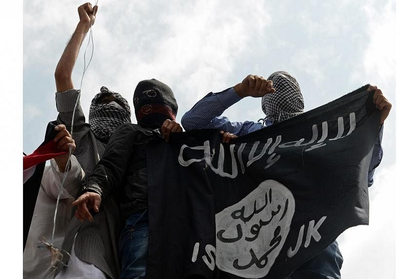 In this photogaph taken on July 18, 2014, Kashmiri demonstrators hold up a flag of the Islamic State in Iraq and Syria (ISIS) during a demonstration against Israeli military operations in Gaza, in downtown Srinagar.&nbsp;ISIS and Al-Qaeda do not yet 