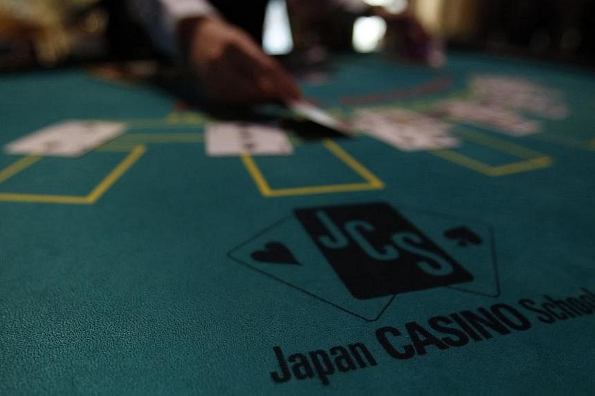A logo of Japan casino school is seen as a dealer puts cards on a mock black jack casino table during a photo opportunity at an international tourism promotion symposium in Tokyo on Sept 28, 2013.&nbsp;Japan's pro-casino lawmakers have given up debat