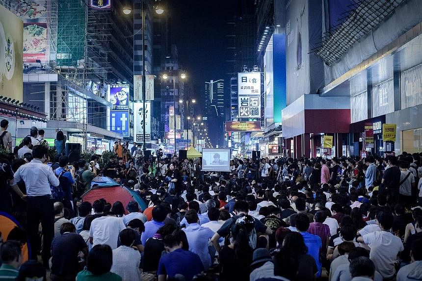 People listen to long-awaited talks between student leaders and senior government officials being broadcasted live at a protest site in the Mong Kok district of Hong Kong, on Oct 21, 2014. -- PHOTO: AFP