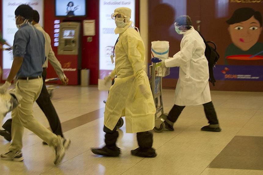 A traveller, who was not cleared after being screened for the Ebola virus on his arrival in India, walks towards an ambulance at the International airport in New Delhi on Aug 26, 2104. -- PHOTO: AFP