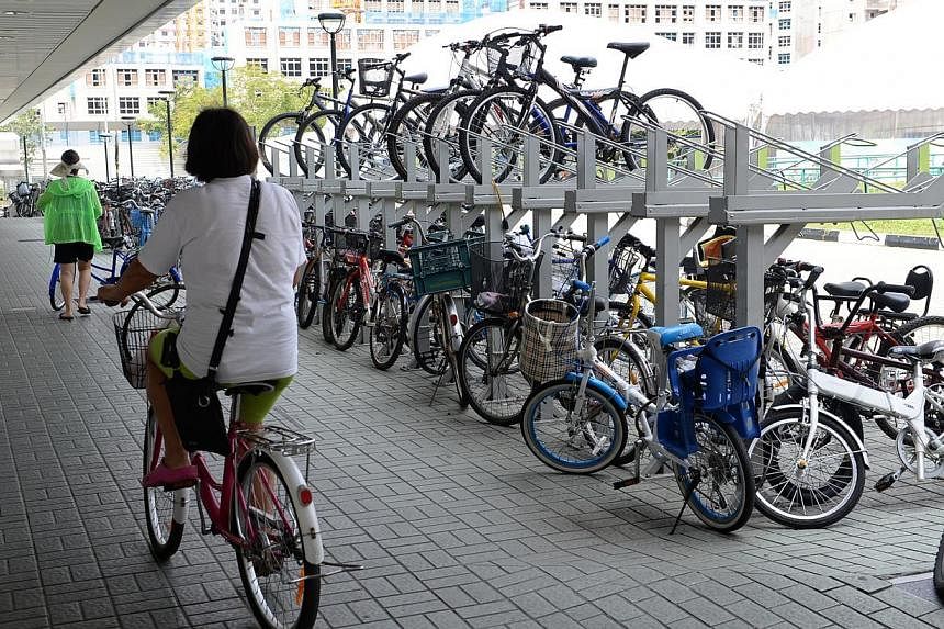 A woman cycling past the bike racks outside Seng Kang MRT station on August 21, 2014. -- PHOTO: ST FILE