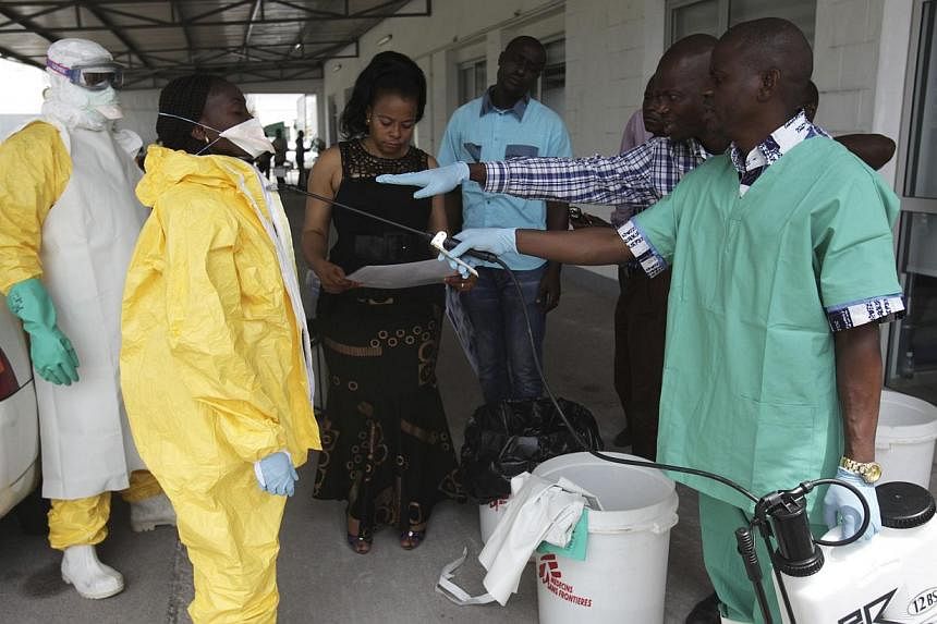 A health worker sprays a colleague with disinfectant during a training session for Congolese health workers to deal with Ebola virus in Kinshasa on Oct 21, 2014. -- PHOTO: REUTERS