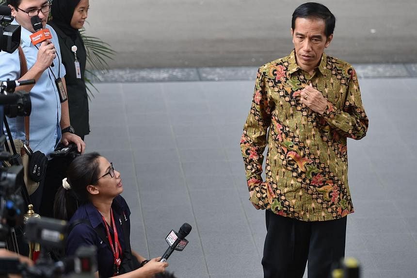 Indonesian President Joko Widodo (right) walks past the journalists outside the Palace in Jakarta on Oct 21, 2014. -- PHOTO: AFP