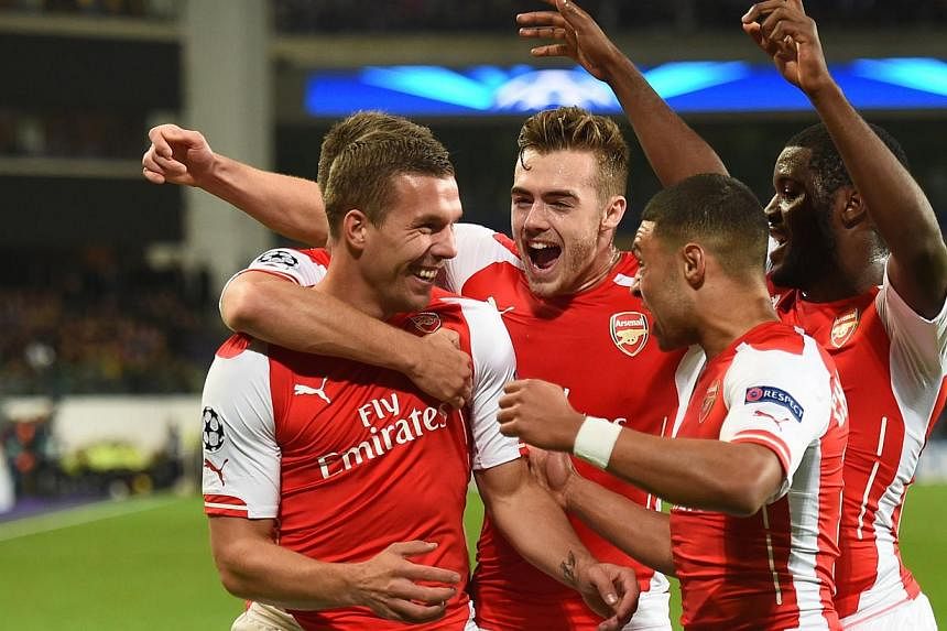 Arsenal's Polish-born German striker Lukas Podolski (left) celebrates with teammates after scoring during a Uefa Champions League group stage football match Anderlecht vs Arsenal at the Constant Vanden Stock stadium in Anderlecht on Oct 22, 2014. -- 